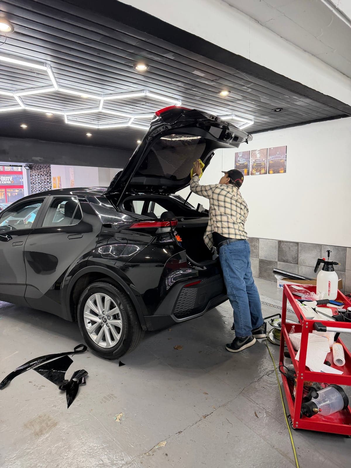 Tint film being hand-fitted to the tailgate glass of a black Toyota C-HR